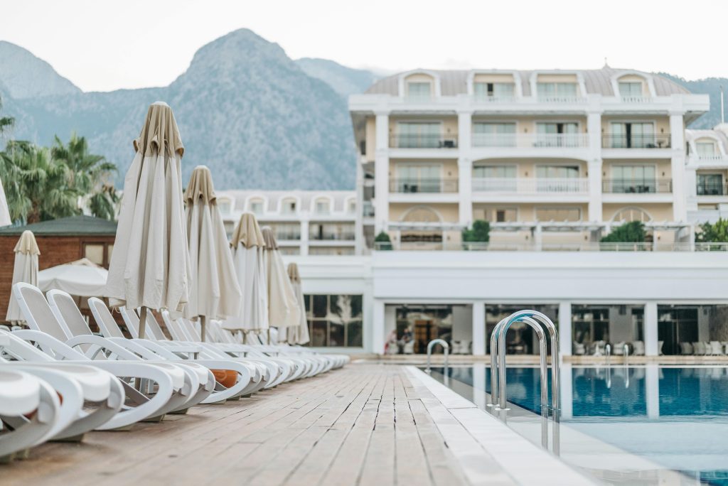 Empty sunloungers and umbrellas by a luxury resort pool with a mountain view.